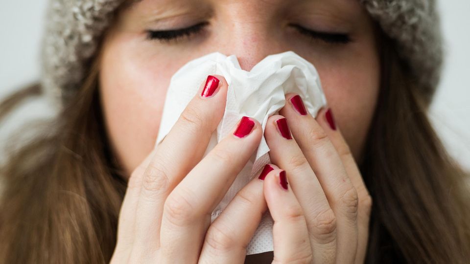 Grippe 2019: Eine Frau hält sich ein Taschentuch vor das Gesicht