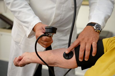 Ein Hausarzt misst in seiner Praxis einer Patientin den Blutdruck