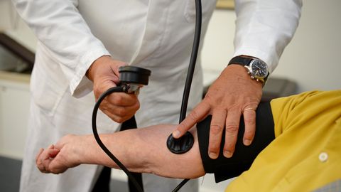 Ein Hausarzt misst in seiner Praxis einer Patientin den Blutdruck
