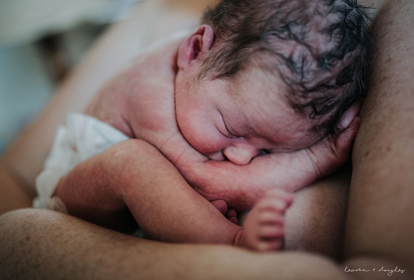 Ein frisch geborenes Babyliegt zusammengerollt auf der Brust der Mutter