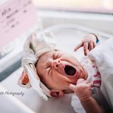 Ein Baby mit einem geknoteten Kopftuch gähnt herzhaft