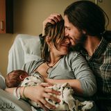 Eine Mutter stillt ihr Baby, der Vater schmust mit ihr