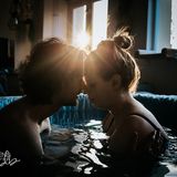 Bei einer Wassergeburt sitzen Vater und Mutter Stirn an Stirn in der Wanne