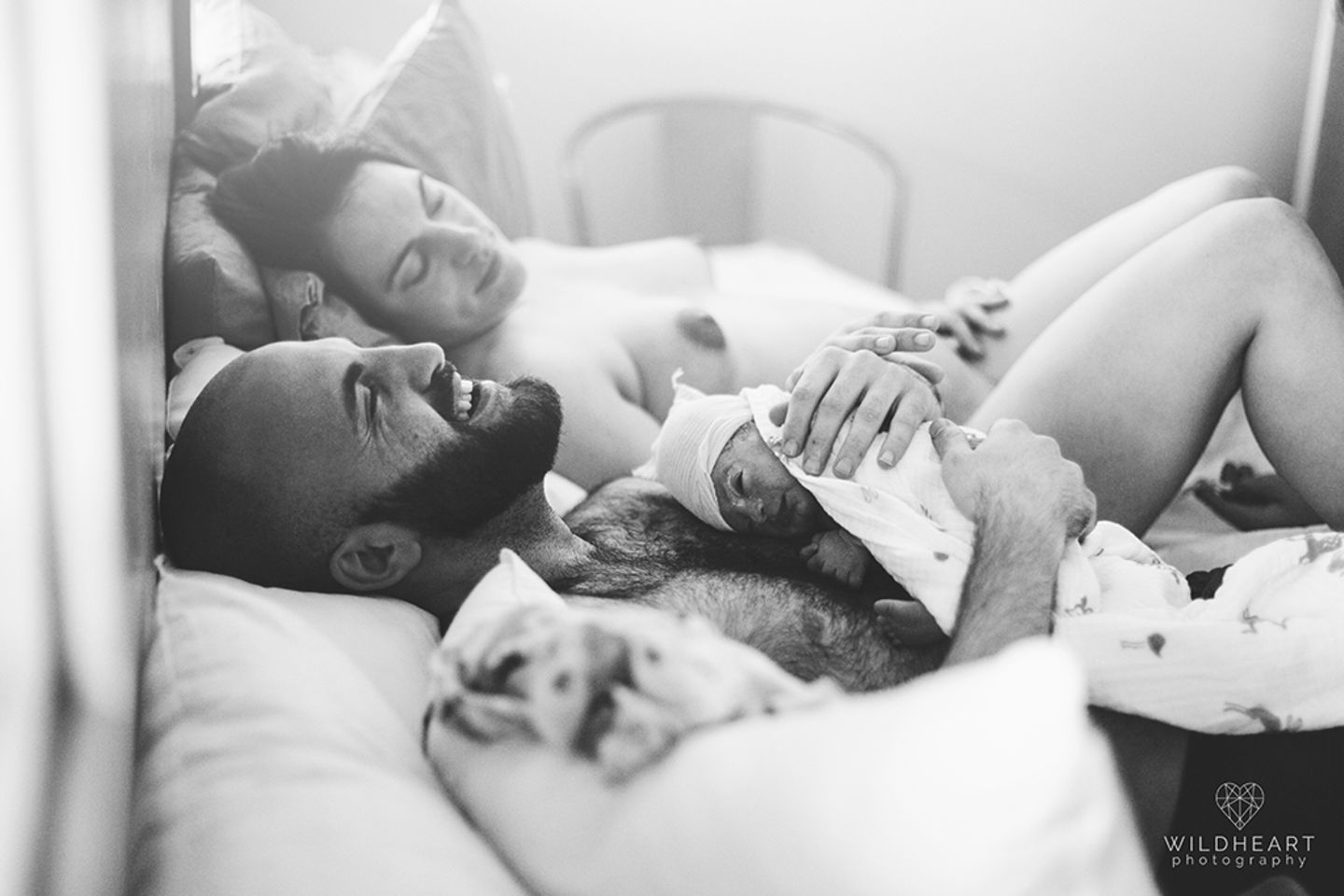 2019 IAPBP Image Competition Die Mutter erholt sich von der Geburt, der Vater hält das Baby und lacht aus vollem Herzen