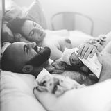 Die Mutter erholt sich von der Geburt, der Vater hält das Baby und lacht aus vollem Herzen