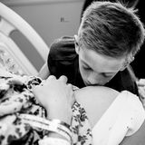 Ein kleiner, weinender Junge küsst den schwangeren Bauch seiner Mutter