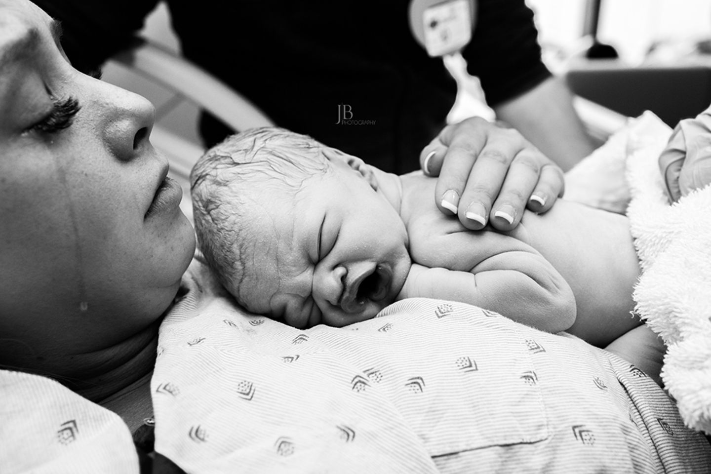 Eine stark geschminkte Mutter hält weinend ihr Baby im Arm