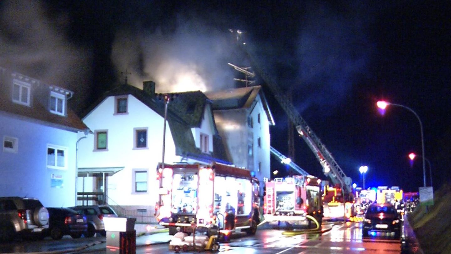 Feuerwehrleute löschen den Brand in einem Mehrfamilienhaus in Lambrecht in Rheinland-Pfalz