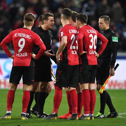 Schiedsrichter Felix Brych diskutiert mit Freiburger Spielern