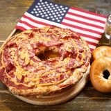 London, Vereinigtes Königreich. Sie sehen: eine Bagelizza. Eine was? Eine Mischung aus Bagel und Pizza, die eine Bäckerei in der britischen Hauptstadt an Passanten verteilt. Der Grund für die Aktion (und die eigenwillige, 1,5 Kilo schwere Kreation): Am Samstag wird nicht nur der National Pizza Day, sondern auch der National Bagel Day gefeiert.