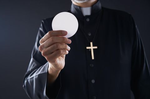 Ein Pastor hält eine Hostie in der Hand