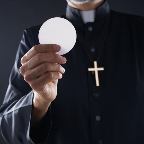 Ein Pastor hält eine Hostie in der Hand