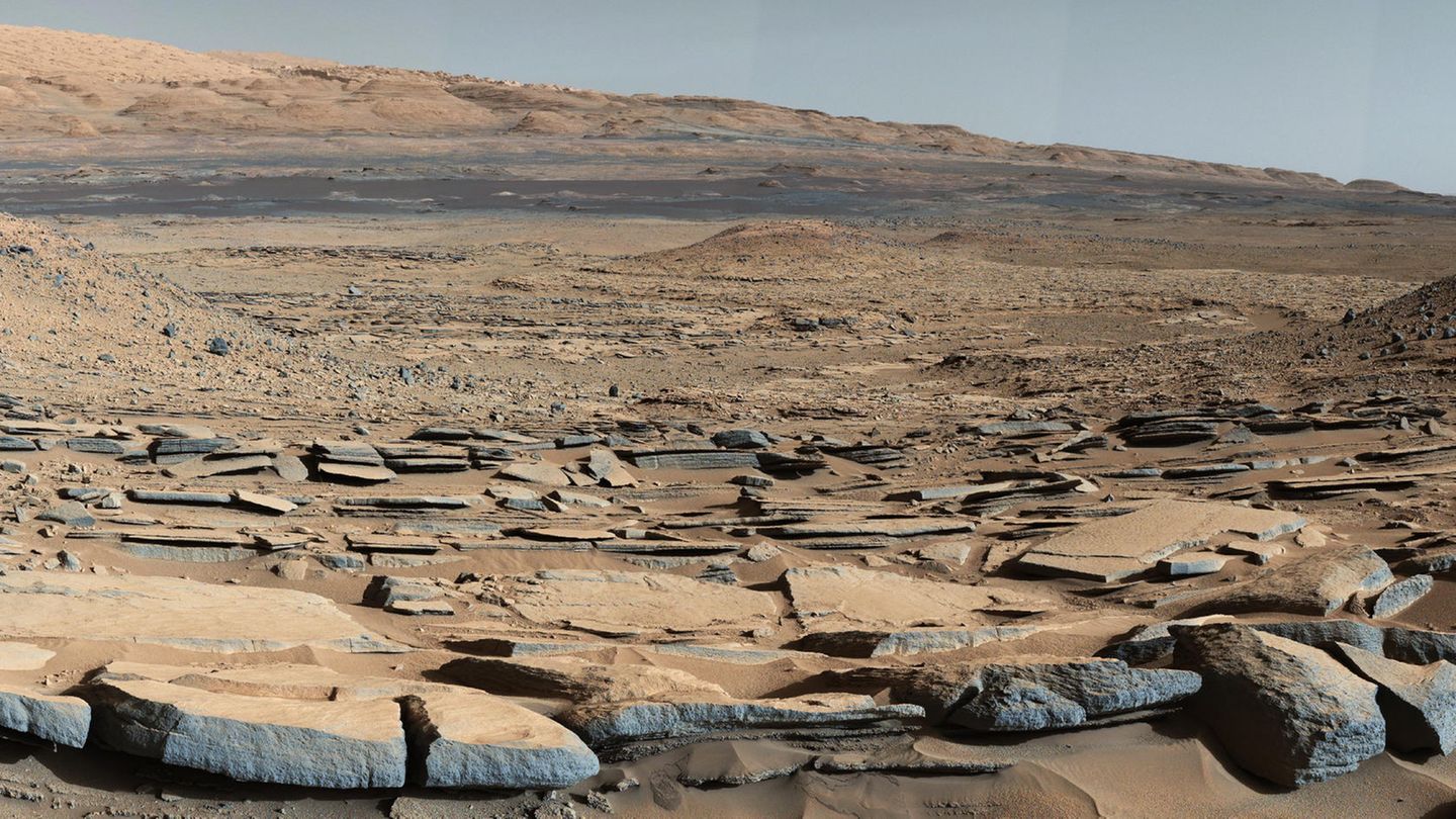 Er sollte nur 90 Tage arbeiten : Blick von der "Kimberley"-Formation auf den Fuß des Bergs "Mount Sharp". Dies deutet darauf hin, dass es einen Wasserfluss in Richtung eines Beckens gab, der vor der Entstehung des Berges existierte. Das Bild stammt aus dem Frühjahr 2018. Das Ende von "Opportunity" begann, als ein monatelanger Sandsturm die Atmosphäre derart verdunkelte, dass die Solarzellen des Roboters nicht mehr genügend Strom zum Aufladen seiner Batterien lieferten. Blick von der "Kimberley"-Formation auf den Fuß des Bergs "Mount Sharp". Dies deutet darauf hin, dass es einen Wasserfluss in Richtung eines Beckens gab, der vor der Entstehung des Berges existierte. Das Bild stammt aus dem Frühjahr 2018. Das Ende von "Opportunity" begann, als ein monatelanger Sandsturm die Atmosphäre derart verdunkelte, dass die Solarzellen des Roboters nicht mehr genügend Strom zum Aufladen seiner Batterien lieferten.