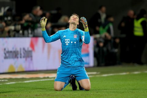 Torwart Manuel Neuer kniet auf dem Rasen und schaut mit erhobenen Armen zum Himmel