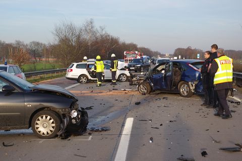 Auf einer Autobahn sind Polizisten und Feuerwehrleute zwischen vier Autowracks unterwegs