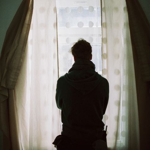 Ein Mann steht am Fenster und ist von hinten zu sehen