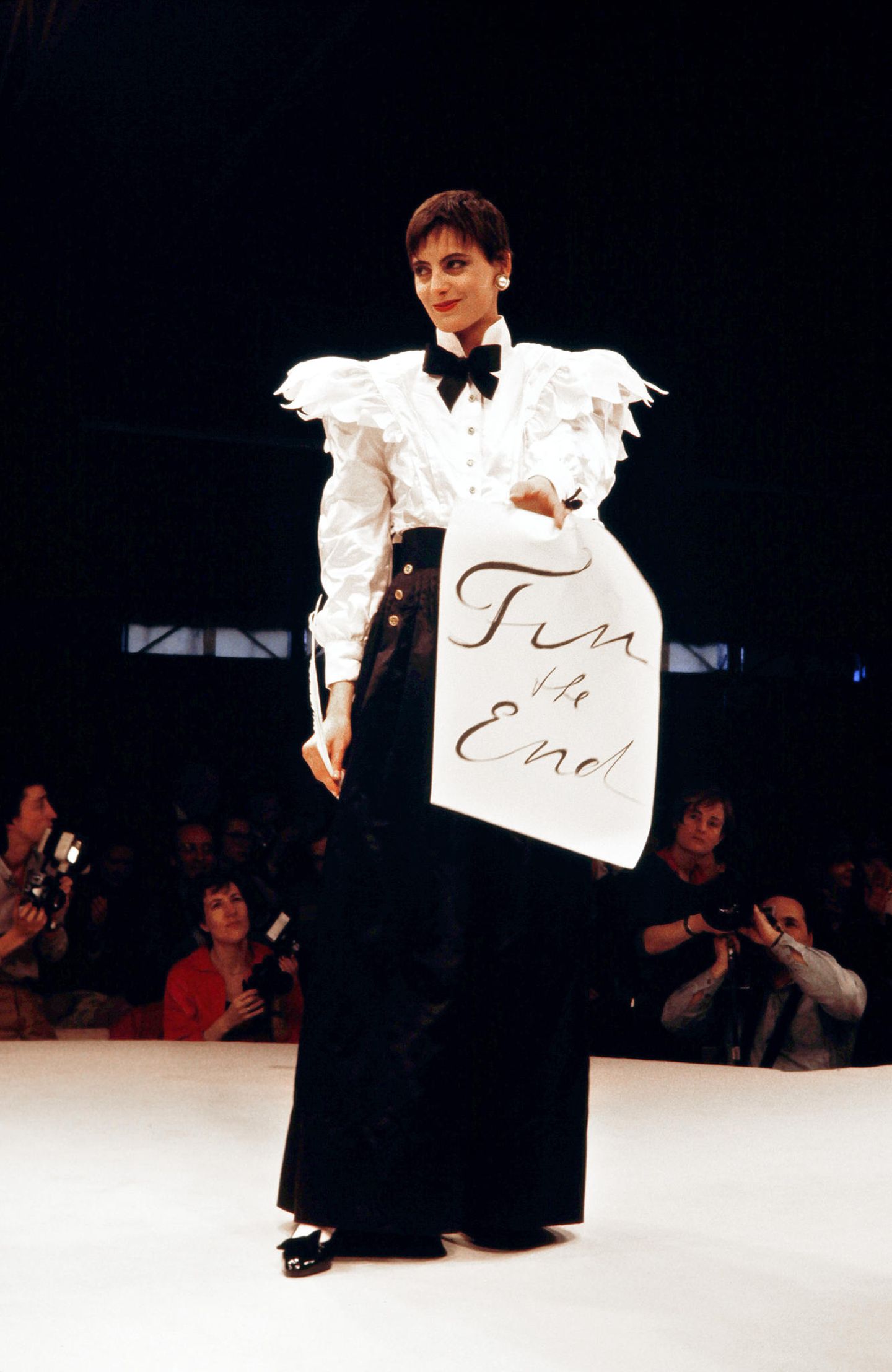 Karl Lagerfeld für Chanel Karl Lagerfeld wurde 1983 Kreativdirektor von Chanel. Er lehnte seine Designs an die Kreationen von Coco Chanel an – nur eben moderner. Das französische Model Ines de la Fressange zeigt sich hier in einem Look der Herbst/Winter-Kollektion von 1984/1985 in Paris, einer der ersten Kollektionen von Karl Lagerfeld für Chanel. Sie präsentiert einen klassischen, aber trotzdem spannenden Chanel-Look in schwarz-weiß. Details wie Schulterpolster und Rüschen, Schleife und die großen Perlen-Ohrringe sind charakteristisch für das Modehaus.
