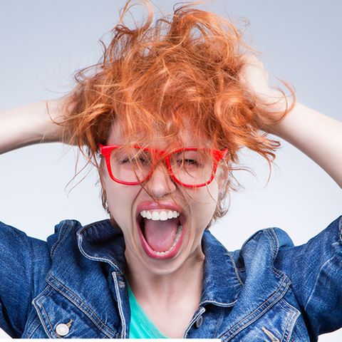 Junge Frau zerwuschelt schreiend ihre Haare