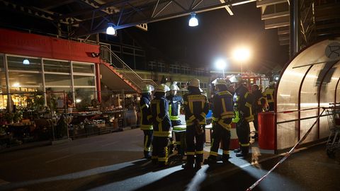 Mehrere Feuerwehrleute stehen im Scheinwerferlicht auf dem Parkplatz eines Einkaufszentrum in Unkel