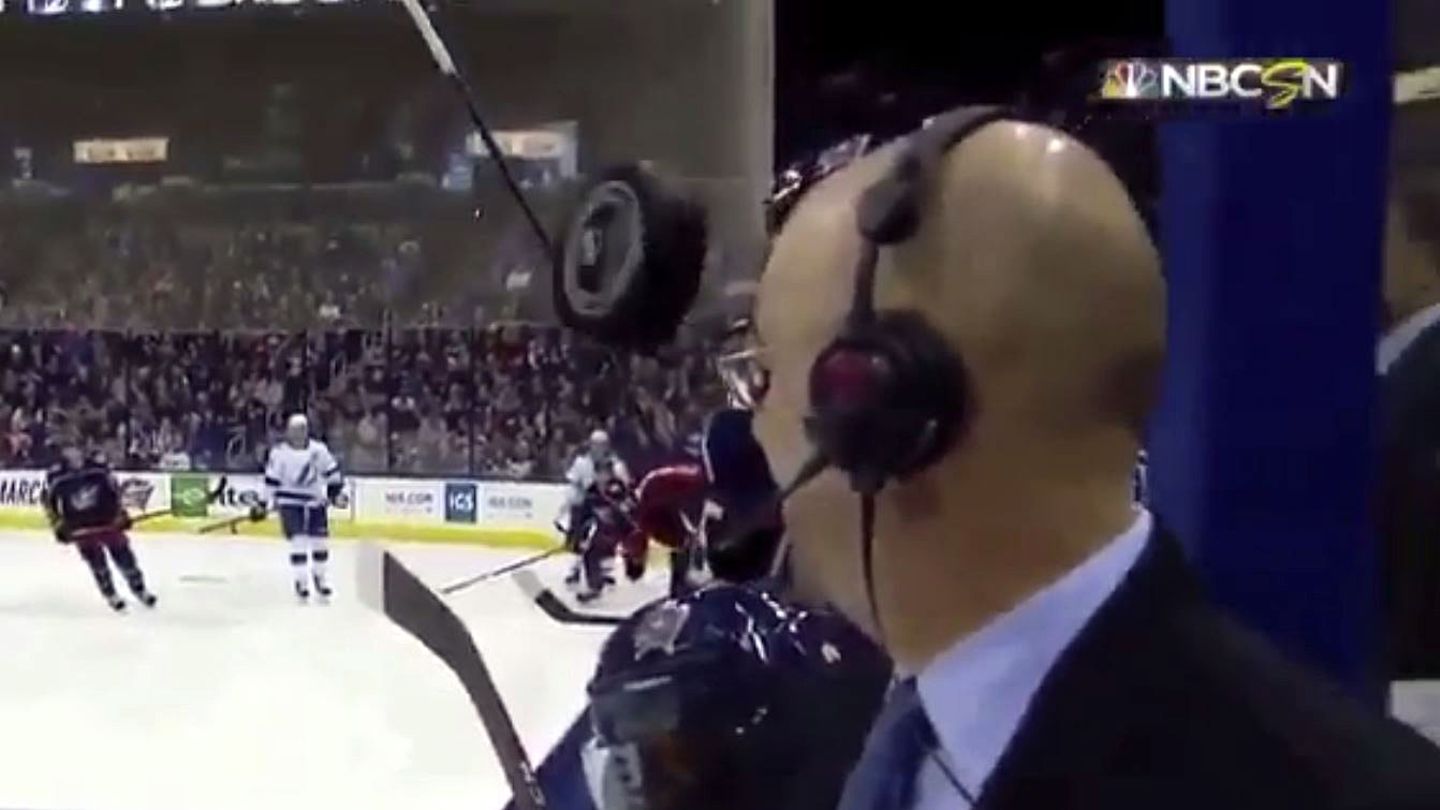 Ein Eishockey-Puck fliegt nur Zentimeter an der Stirn eines TV-Kommentators vorbei