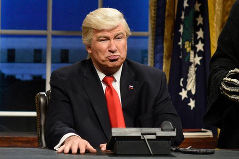 Schauspieler Alec Baldwin sitzt als Donald Trump in einer Kulisse, die ans Oval Office erinnert
