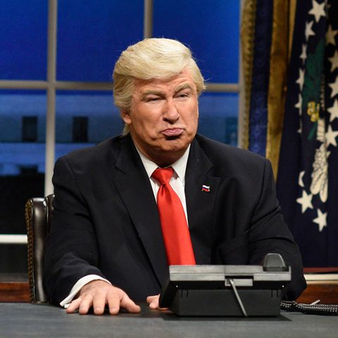 Schauspieler Alec Baldwin sitzt als Donald Trump in einer Kulisse, die ans Oval Office erinnert