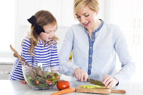 Mutter und Tochter bereiten einen Salat in der Küche vor.
