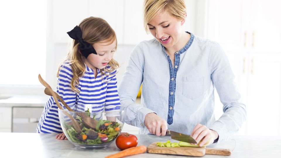 Gesunde Ernährung : Mutter und Tochter bereiten einen Salat in der Küche vor. Mutter und Tochter bereiten einen Salat in der Küche vor.