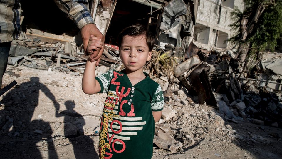 Omran hält die Hand seines Vaters, als er durch das Viertel Kaum al-Qaterdschi geht. Hier wurde er nach dem Bombeneinschlag gerettet.