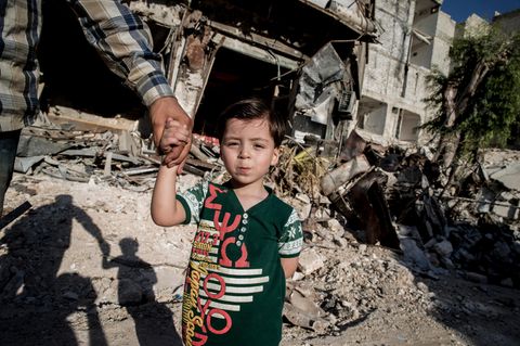 Omran hält die Hand seines Vaters, als er durch das Viertel Kaum al-Qaterdschi geht. Hier wurde er nach dem Bombeneinschlag gerettet.