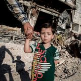 Omran hält die Hand seines Vaters, als er durch das Viertel Kaum al-Qaterdschi geht. Hier wurde er nach dem Bombeneinschlag gerettet.