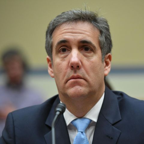 Michael Cohen sitzt in Anzug und Krawatte vor einem Mikrofon und scheint gerade einer Frage zu lauschen