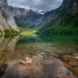 Obersee, Berchtesgaden, Bayern  Wie eine Spiegelung der Felsen rund um den See erscheint die Wasseroberfläche des Obersees. Das sehr klare Wasser des Sees macht das möglich. Da es keinen Bootsverkehr auf dem See gibt und er geschützt liegt, wird dieser Effekt noch verstärkt. Die Wanderwege rund um den Obersee führen auch zum nördlich gelegenen Königssee. Dieser ist durch einen Moränenwall vom Obersee getrennt.