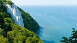 Kreidefelsen Rügen, Mecklenburg-Vorpommern   Ägäis oder doch Rügen? Durch die Reflexion der Kalkpartikel wirkt das Wasser rund um die Kreidefelsen auf Rügen enorm blau. Das gilt vor allem, wenn die Sonne scheint. Der Königsstuhl ist die berühmteste Kreidefelsformation der Stubbenkammer im Nationalpark Jasmund auf Rügen. Ganz ungefährlich sind die Felsen allerdings nicht. Immer wieder brechen Teile der Felsformationen bedingt durch die poröse Konsistenz ins Meer. Wer sich allerdings auf den befestigten Wegen aufhält, kann hier ein wunderschönes Naturschauspiel beobachten.