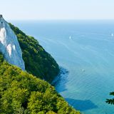 Kreidefelsen Rügen, Mecklenburg-Vorpommern   Ägäis oder doch Rügen? Durch die Reflexion der Kalkpartikel wirkt das Wasser rund um die Kreidefelsen auf Rügen enorm blau. Das gilt vor allem, wenn die Sonne scheint. Der Königsstuhl ist die berühmteste Kreidefelsformation der Stubbenkammer im Nationalpark Jasmund auf Rügen. Ganz ungefährlich sind die Felsen allerdings nicht. Immer wieder brechen Teile der Felsformationen bedingt durch die poröse Konsistenz ins Meer. Wer sich allerdings auf den befestigten Wegen aufhält, kann hier ein wunderschönes Naturschauspiel beobachten.