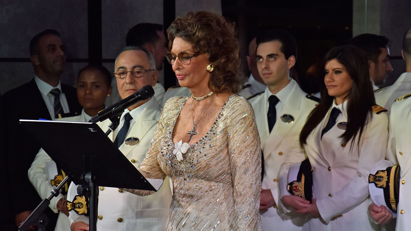 Fast jedes Schiff von MSC Cruises hat Sophia Loren getauft. Die Film-Diva hält eine kurze Ansprache. Doch wie wird das Band zerschnitten, damit die Champagnerflasche an der Bordwand zerspringen kann? Die 84-Jährige sagt "five" und gemeinsam mit dem Publikum wird abwärts gezählt.