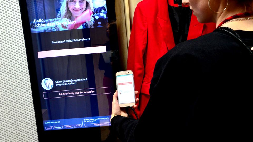 Auf dem großen Display in der Umkleidekabine kann man eine Größe nachbestellen oder einen Fashion Assistent um Hilfe beten Auf dem großen Display in der Umkleidekabine kann man eine Größe nachbestellen oder einen Fashion Assistent um Hilfe beten