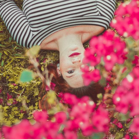 Ein Mädchen liegt in einer Blumenwiese