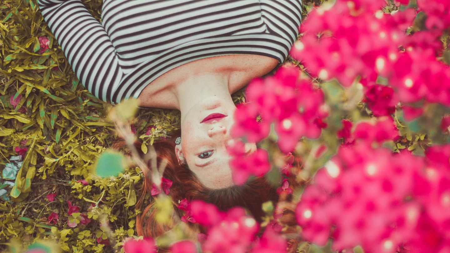 Ein Mädchen liegt in einer Blumenwiese