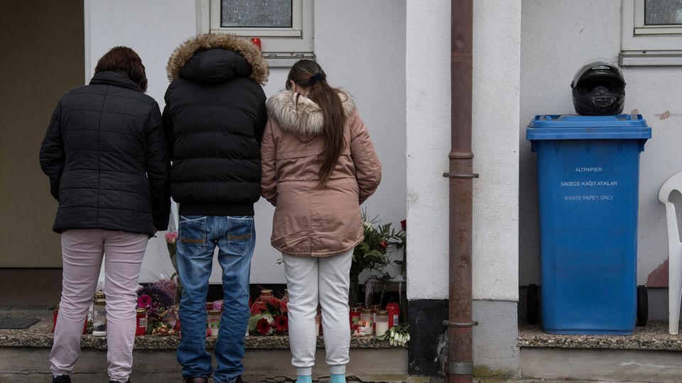 Trauernde Nachbarn und Freunde stehen vor dem Haus in Worms, in dem eine 21-Jährige getötet worden war