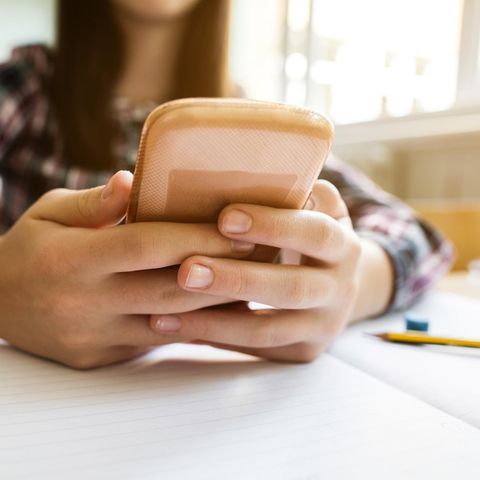 Schülerin, die ihr Handy nutzt