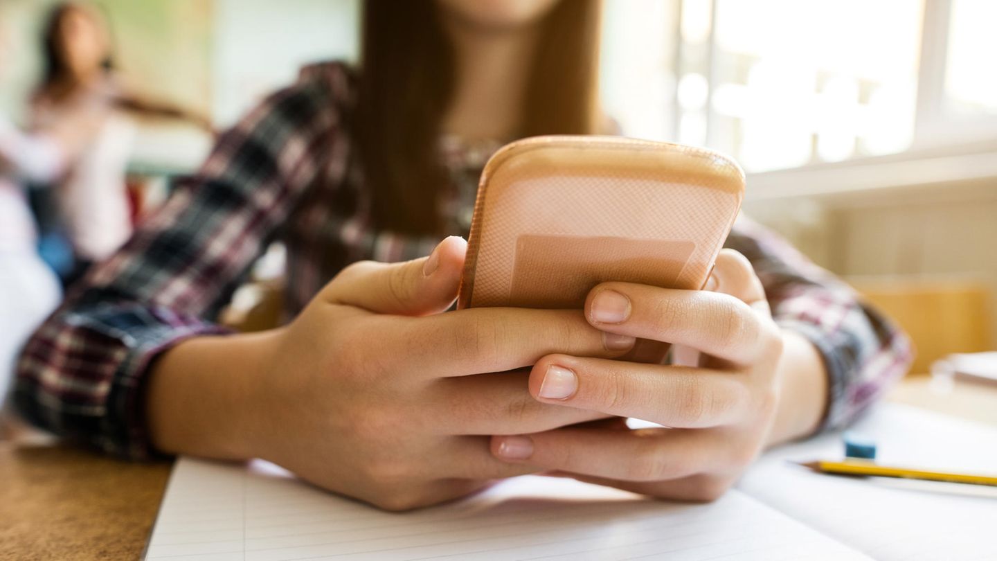 Schülerin, die ihr Handy nutzt