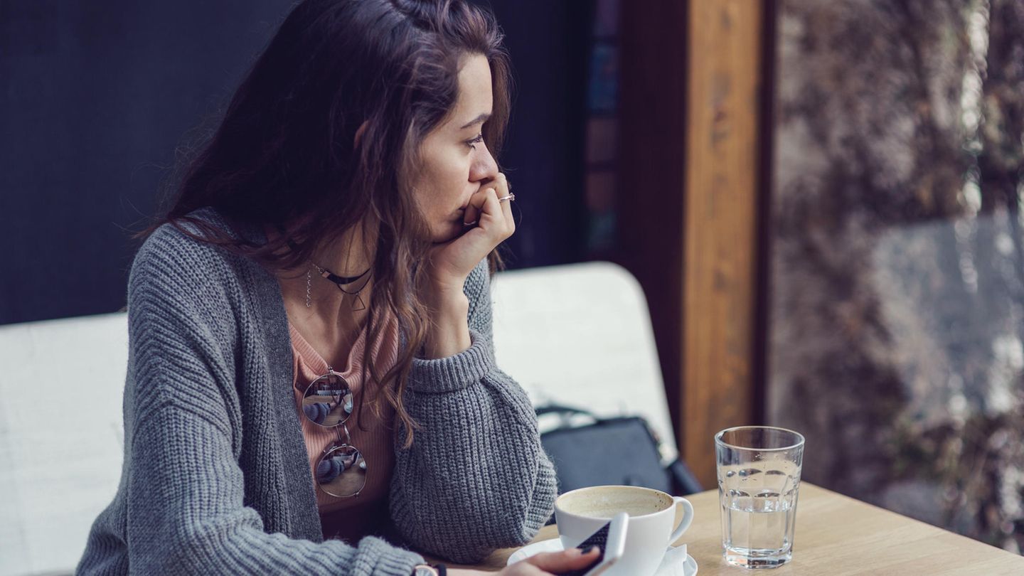 Eine Frau sitzt allein im Café und guckt aus dem Fenster