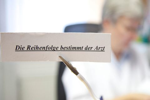 Ein Schild weist in einer Arztpraxis darauf hin, dass die Reihenfolge der Patienten vom Arzt bestimmt wird