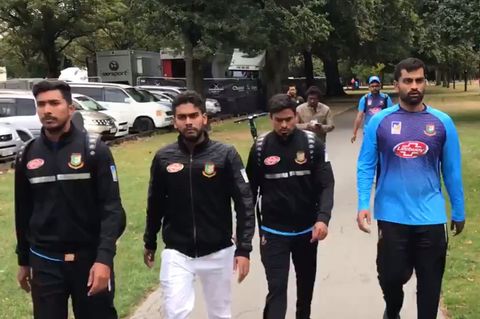 Mehrere Männer in Trainingskleidung gehen einen Weg in einem Park entlang
