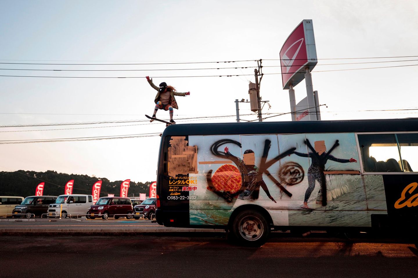 Sky springt mit dem Skateboard vom Autodach eines Tourbusses