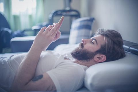 Mann mit Handy im Bett