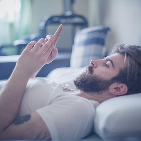 Mann mit Handy im Bett