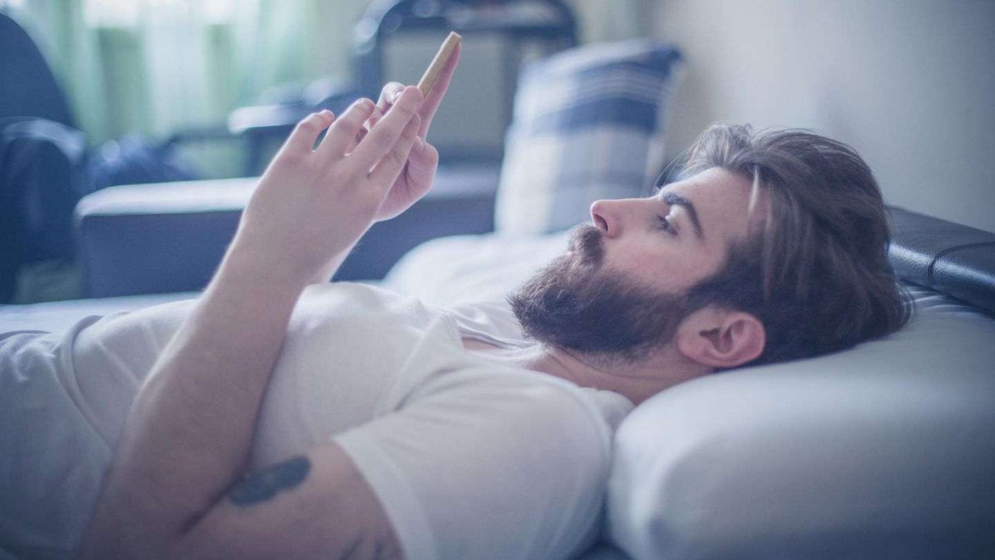 Mann mit Handy im Bett