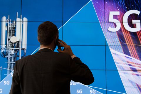 Ein Mann telefoniert vor einer Werbetafel für den 5G-Mobilfunkstandart